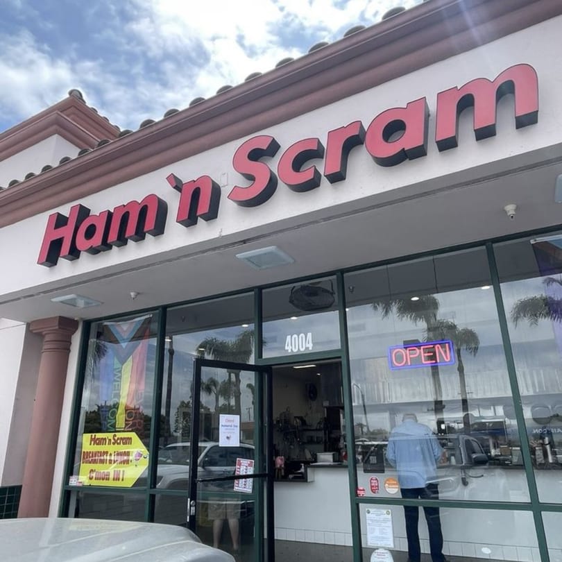 The exterior of Ham 'n Scram restaurant with a red sign, glass doors, and an "OPEN" neon sign.